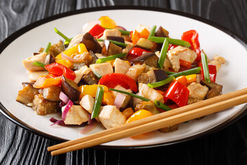 Chinese fried chicken with eggplant, pepper and onion in spicy soy sauce close-up in a plate on the table. horizontal