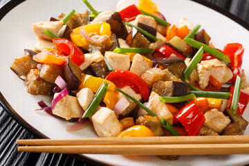 Delicious fried chicken with eggplant, pepper and onions close-up in a plate on the table. horizontal