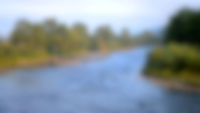 Blurred background. Wide shallow river in the mountains in summer sunny morning