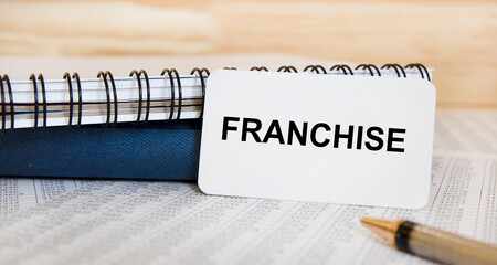 The inscription on the FRANCHISE business card. Next to the reports, books.