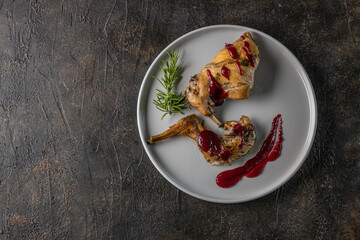 Oven Baked rabbit legs with cranberry sauce and rosemary. Rabbit confit