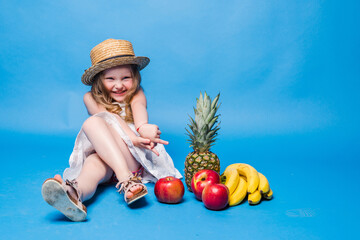 Little girl playing with fruits isolated on a blue background