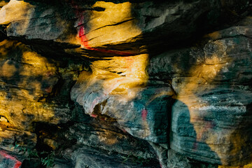 Three-dimensional stone rocks of different shapes in the rays of the setting sunlight. Old rocky formations with stripes of white and red paint