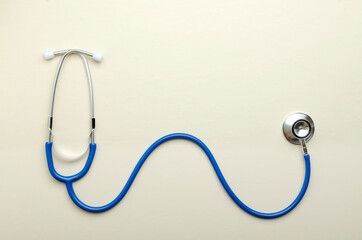 Top view of blue stethoscope in wavy position on the light beige surface.Empty space
