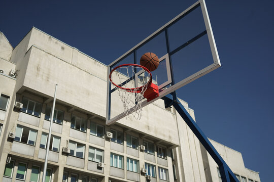 Image of basketball shot in hoop on city sports ground at summer day