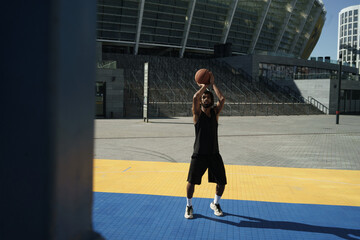 Fototapeta na wymiar Image of african american guy playing basketball on city sports ground
