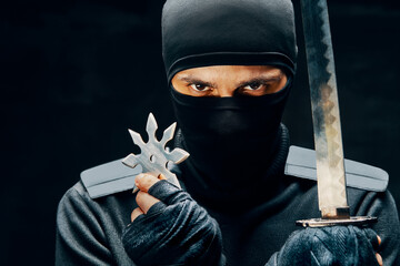 Ninja samurai warrior fighter with a sword and shuriken over black background © GVS
