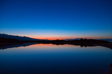 Fototapeta na wymiar Dawn of the sun at sea. The rising sun behind the mountains. Kyrgyzstan.