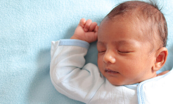 close up photo of a neonatal infant baby sleeping in peace on a sky colored towel