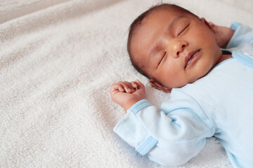 a one month old baby sleeping and swaddled in white cloth lying in white cloth background
