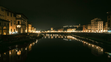 View of European city with bridge and reflections on the water of builds and city lights by night.
