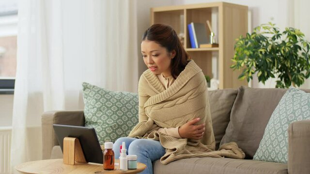 medicine, healthcare and technology concept - sick young asian woman having video call or online consultation on tablet pc computer at home