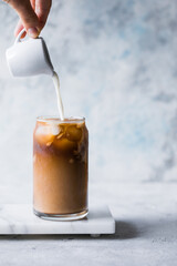 Frappe milk shake coffee in tall glass on blue background.