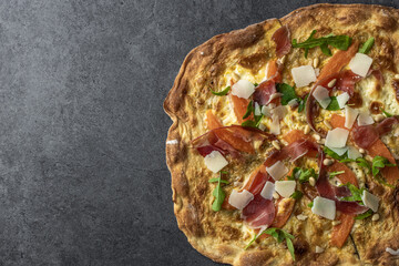 Pizza with jamon serrano prosciutto, melon, arugula salad and pine nuts. Flammkuchen, Tarte Flambee. Top view. Copy space