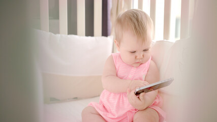 Baby girl holding smartphone in hands. Beautiful toddler girl with phone