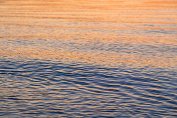 Clear water texture in blue and orange. Background of the ocean and the sea backlit by the sun. Natural water