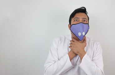 a male doctor in mask and white coat holding his neck with both hands with choking expression isolated in white grey background with space for text