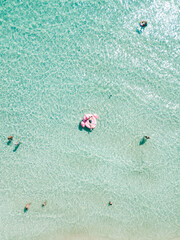 Aerial view of young sexy girl in black swimwear lie on inflatable pink flamingo in azure sea water, swim, sun bathe relax on beach Punta Prosciutto Italian Maldives Puglia Italy. Summer time vacation