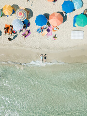 Aerial view of two young women in swimwear lie on sand beach Punta Prosciutto Puglia Italy. Italian...
