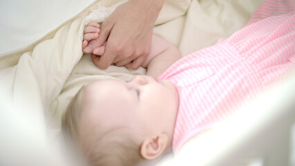 Obraz na płótnie Canvas Little girl sleeping in bed. Mother hand stroking sleeping child