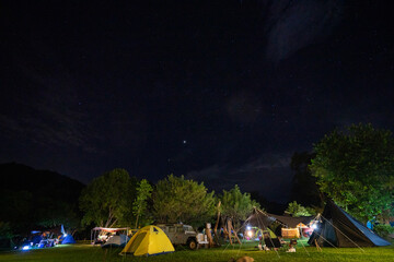 Fototapeta na wymiar Camping and tent on green grass with stars in nature park at night