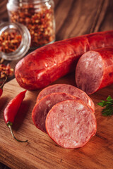 Sliced smoked calabrese sausage in a wooden table with ingredients - Close-up