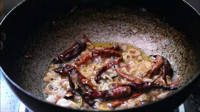 Roasting onions, dried red chilli and curry leaves in oil to make tadka. Tadka is used in Indian dishes to improve taste.