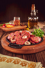 Sliced smoked calabrese sausage with onion in a wooden background - Brazilian appetizer