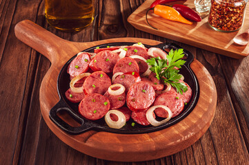 Sliced smoked calabrese sausage with onion and calabrese pepper in a wooden background - Brazilian...