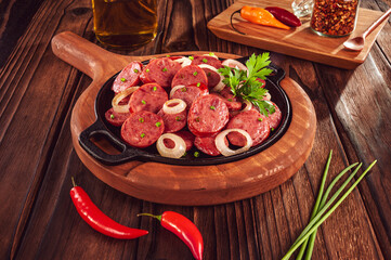 Sliced smoked calabrese sausage with onion and calabrese pepper in a wooden background - Brazilian appetizer
