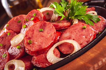 Sliced smoked fried calabrese sausage with onion - Brazilian appetizer close-up