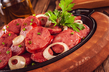 Sliced smoked fried calabrese sausage with onion - Brazilian appetizer close-up