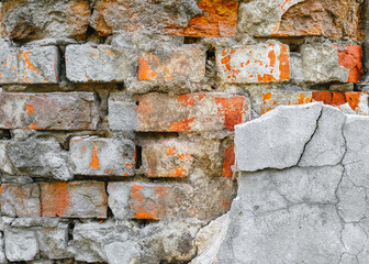 The texture of an old wall of red, orange uneven bricks with gray cement and concrete. Photography,...