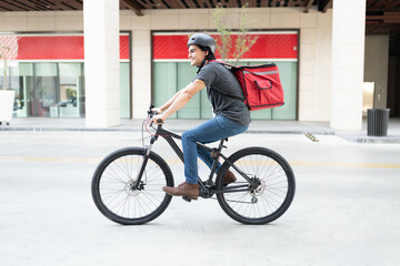 Delivery Man With Backpack Cycling On Street