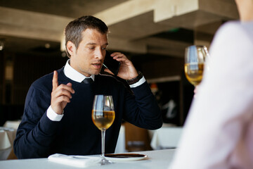Handsome businessman dressed in the suit drinking wine. Businessman talking to the phone..