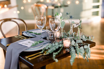 An elegant table decorated with gray napkins, greenery, garland for a simple wedding day