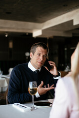 Handsome businessman dressed in the suit drinking wine. Businessman talking to the phone..
