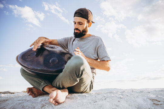 Musician hands playing handpan drum in nature scene