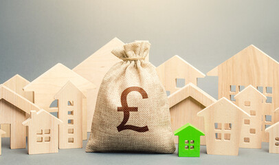 Obraz premium British pound sterling money bag and a city of house figures. City municipal budget. Buying real estate, fair price. Development, renovation of buildings. Investments. Cost of living. Property tax.