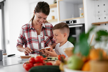Mother and son making breakfast. Mother and son eating sandwich in kitchen..