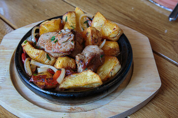 Meat in a frying pan, baked with vegetables and potatoes. Dish of Mediterranean cuisine. Restaurant shooting.