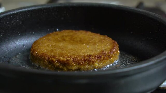 Toasted cutlet with a crust, fried in a pan in oil. Close-up frying juicy minced beef patties burgers in frying pan. Tasty homemade burger fried. Close-up of beef cutlet for burger is fried in hot pan