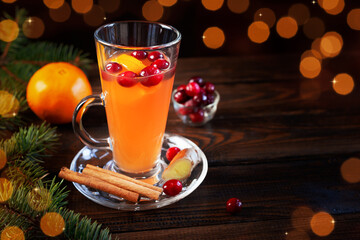 Orange and cranberry non-alcoholic punch with orange slices and spices on a dark wooden table. Christmas drink