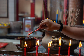 Hand of woman is burning incense in a Chinese temple.