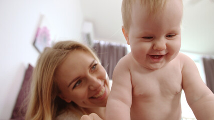 Naked baby with five teeth smile. Happy baby with mother smiling and have fun