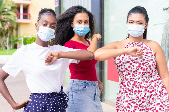 Young girls wearing face mask doing new social distancing greet with elbows for preventing corona virus spread. Covid 19 and friendship concept