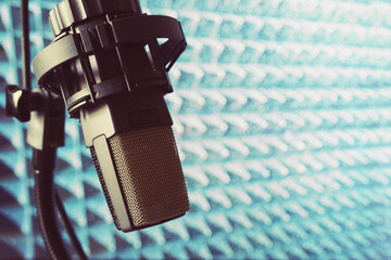 Microphone in recording studio on acoustic foam panel background, close up, soft focus