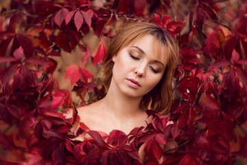 close-up portrait of a woman in red leaves. Autumn portrait of a beautiful woman