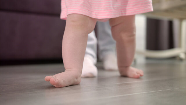 Little baby learning walk on floor. Infant doing first steps with father © stockbusters