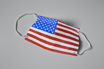 Medical protective mask with USA flag pattern on light grey background, top view. Dangerous virus